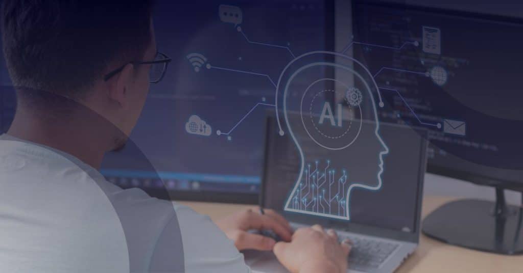 Person using laptop with dual monitors displaying AI-related graphics, illustrating Microsoft Copilot's role in enhancing productivity and efficiency in business environments.