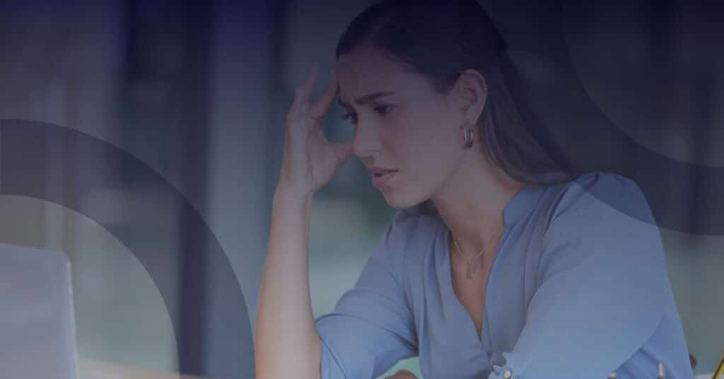 Woman with a concerned expression looking at a laptop, illustrating frustration with outdated IT systems in not-for-profit organizations.
