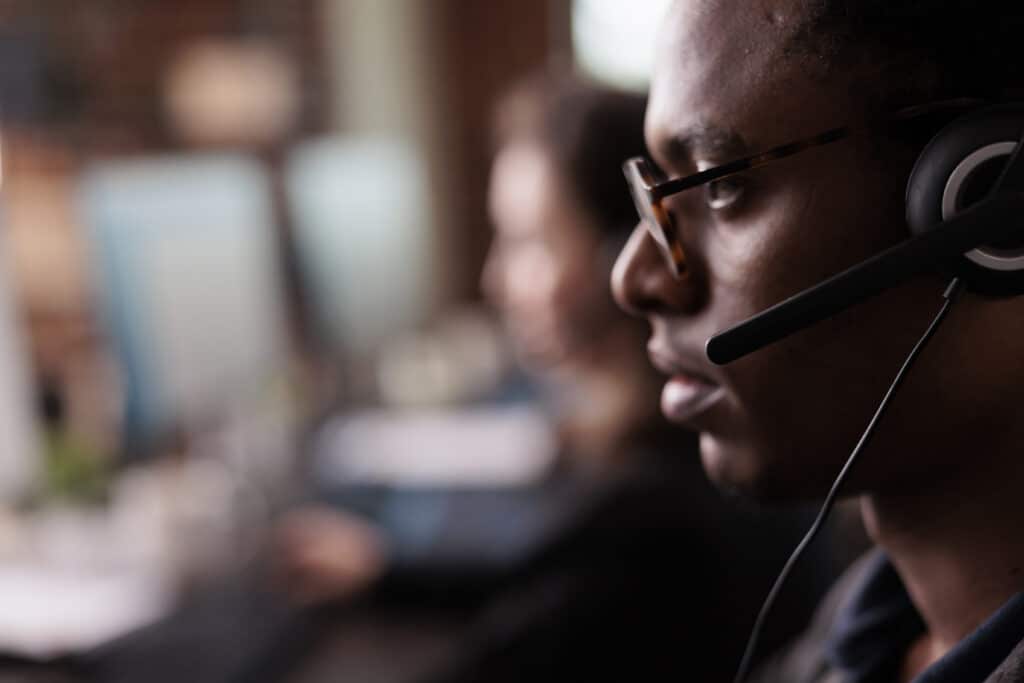 Customer service representative wearing a headset, focused on assisting clients, with computer screens in the background, representing Azure managed services support.