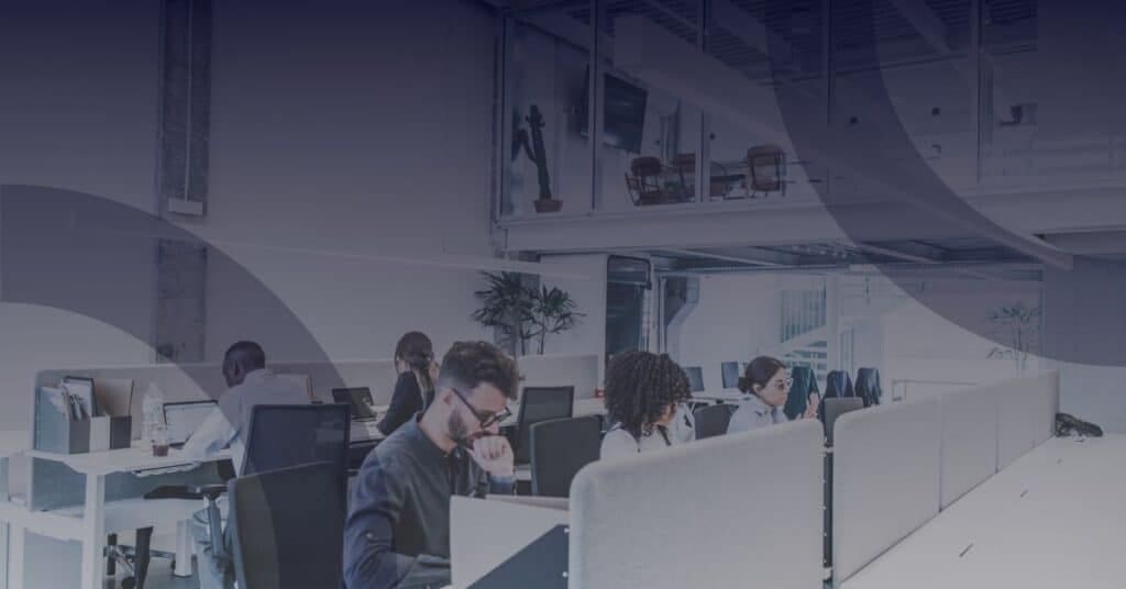 Office environment with employees using computers, highlighting productivity and collaboration, relevant to Microsoft 365 managed services.