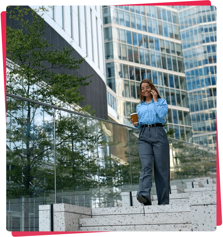 Confident businesswoman walking downstairs in Docklands, holding coffee and smartphone, showcasing professionalism and urban environment.
