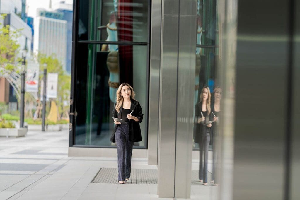 Focused businesswoman walking in urban setting, holding a tablet, reflecting modern IT solutions and professional services offered by Reliable Networks in the Docklands area.