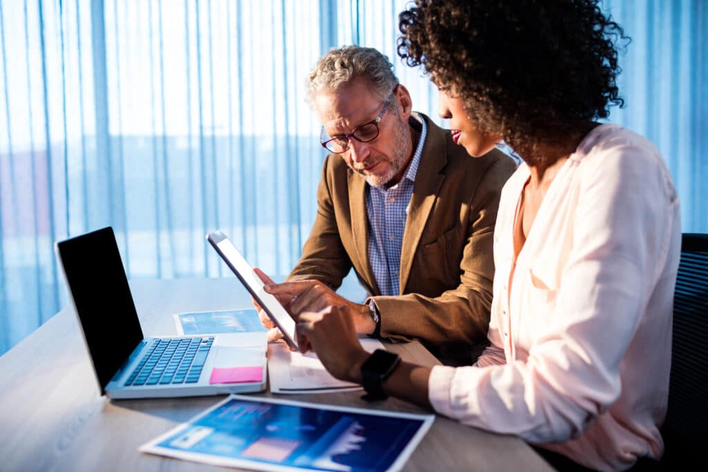 Two people collaborating in an office reviewing tablet and laptop, illustrating managed IT support services.