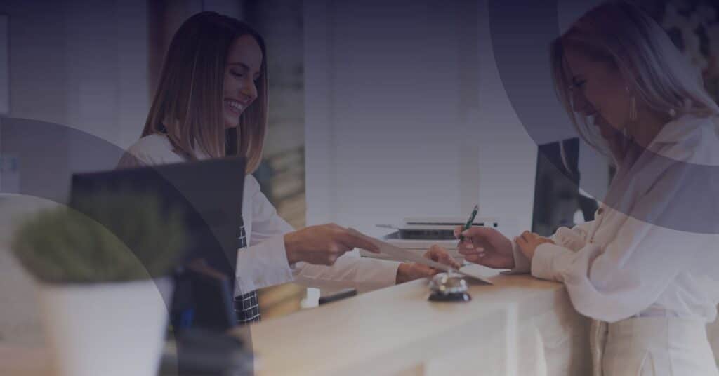 Receptionist assisting a member at a private club, showcasing personalized service and member experience enhancement through technology.